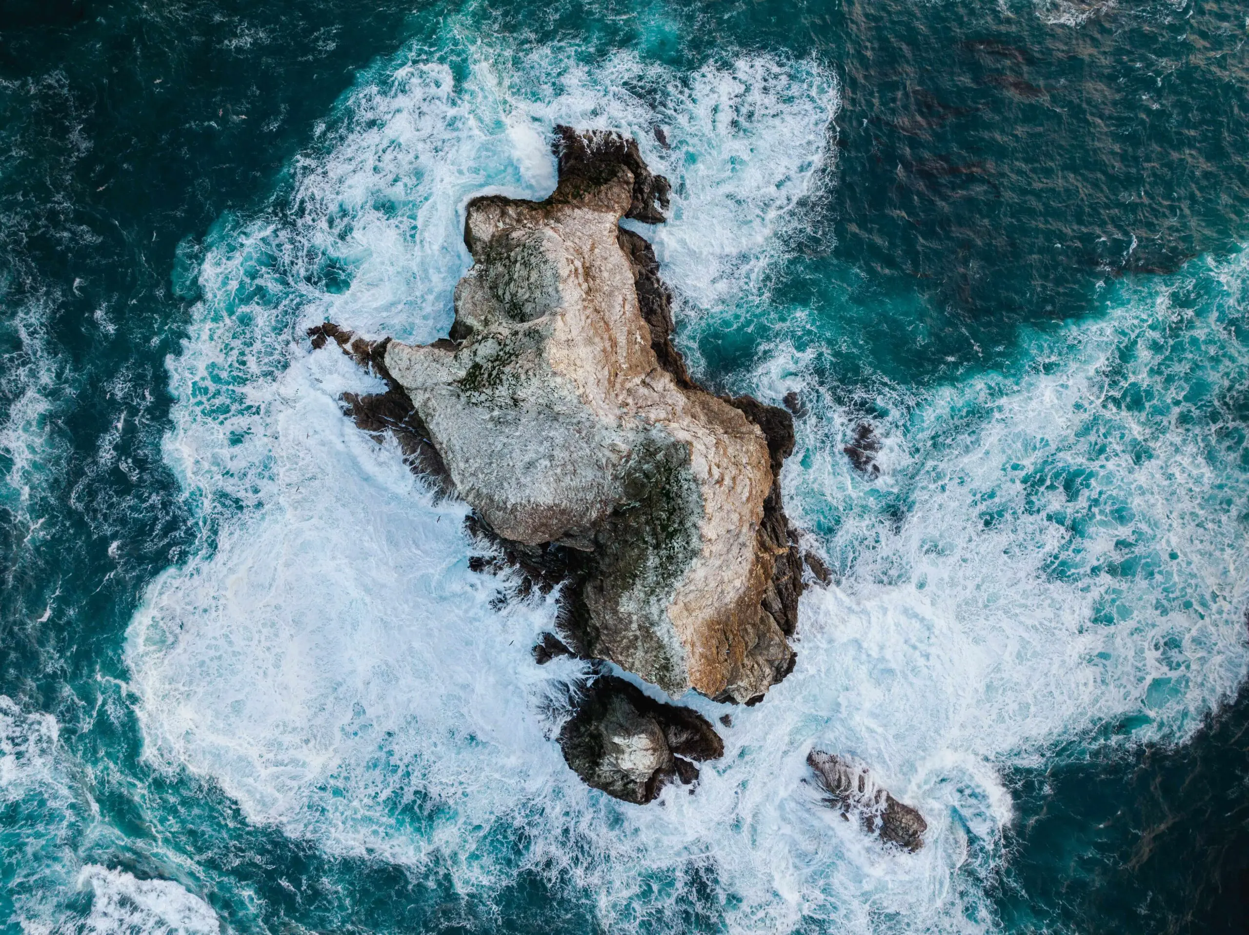 Aerial photo of waves crashing into rocks